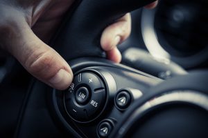 Driver pressing cruise control on steering wheel