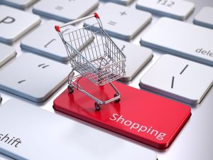 miniature shopping cart on top of red shopping key on keyboard